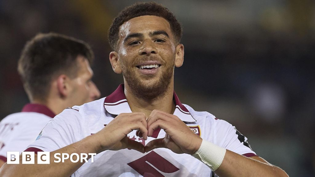 Che Adams looks at the camera and makes a heart shape with his hands while wearing Torino's white and dark red kit.