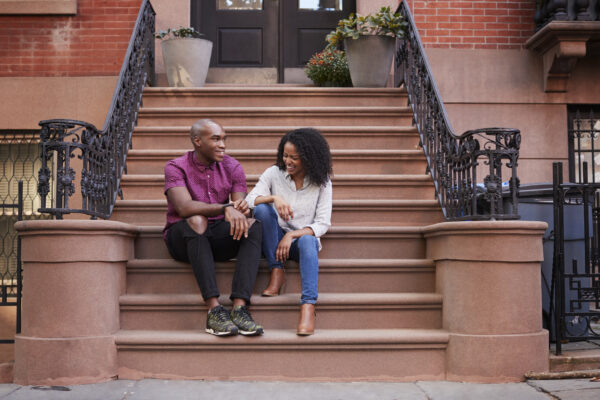 A couple talk in front of brownstone