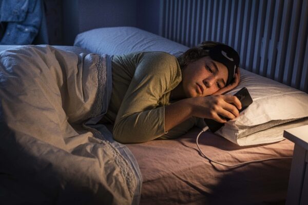 Teenage girl suffering insomnia using smartphone at night