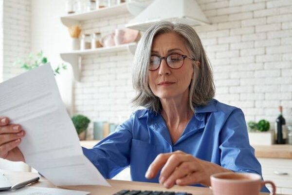 A woman looks over her 401(k) account statement to determine whether she should make catch-up contributions.