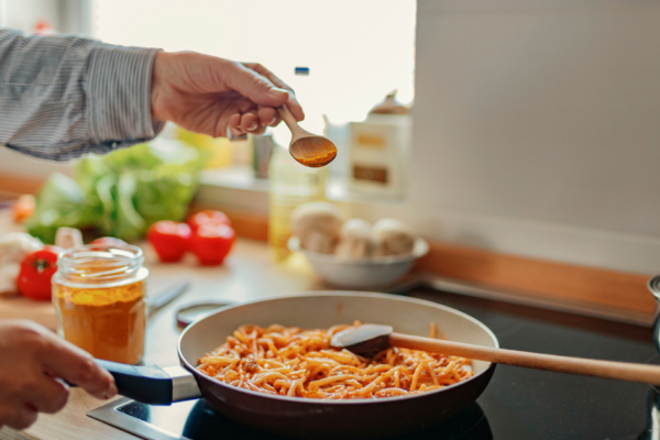 Hand sprinkling turmeric on pasta