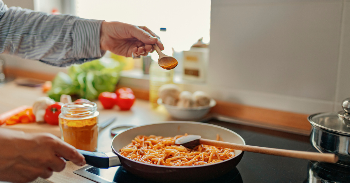 Hand sprinkling turmeric on pasta