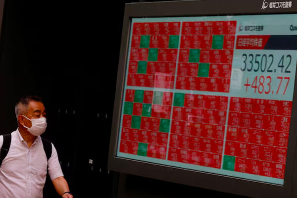 A man looks at an electric board displaying the Nikkei stock average outside a brokerage in Tokyo.