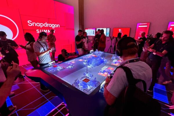 Journalists gather under the red glow of demos at Qualcomm&apos;s Snapdragon Summit.