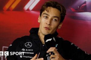 Mercedes driver George Russell speaking into a microphone with the F1 logo during the drivers' press conference for the Las Vegas Grand Prix