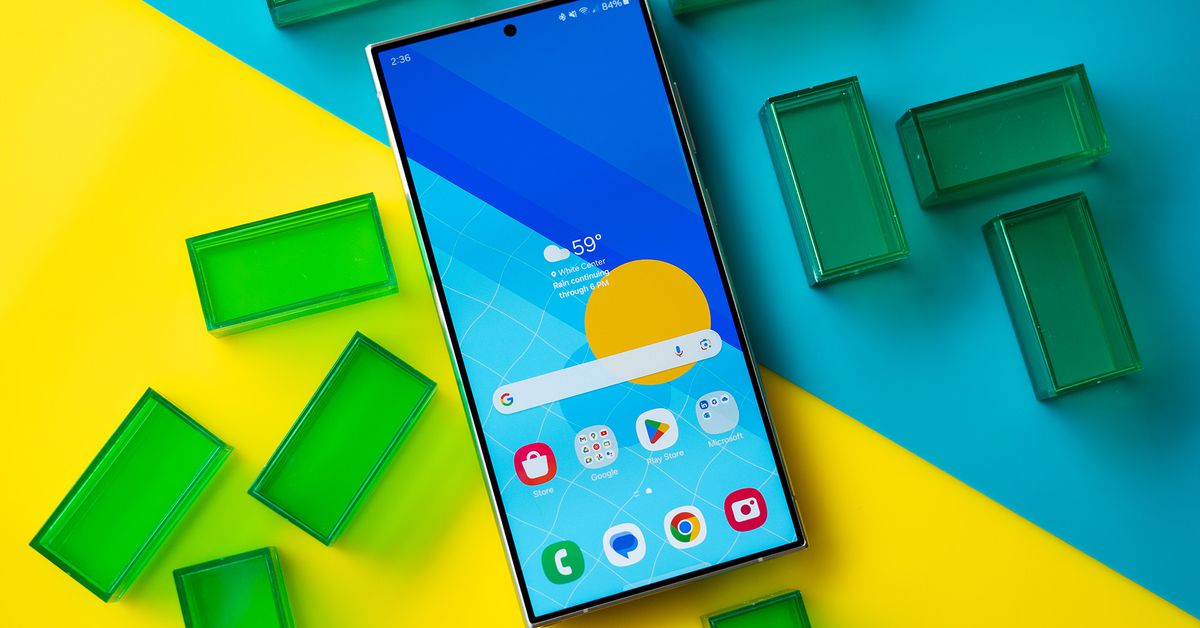 Samsung Galaxy S24 Ultra showing a blue and yellow homescreen, on a blue and yellow background with green translucent rectangles.