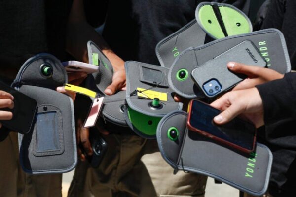 A student uses their cell phone after unlocking the pouch that secures it from use during the school day.