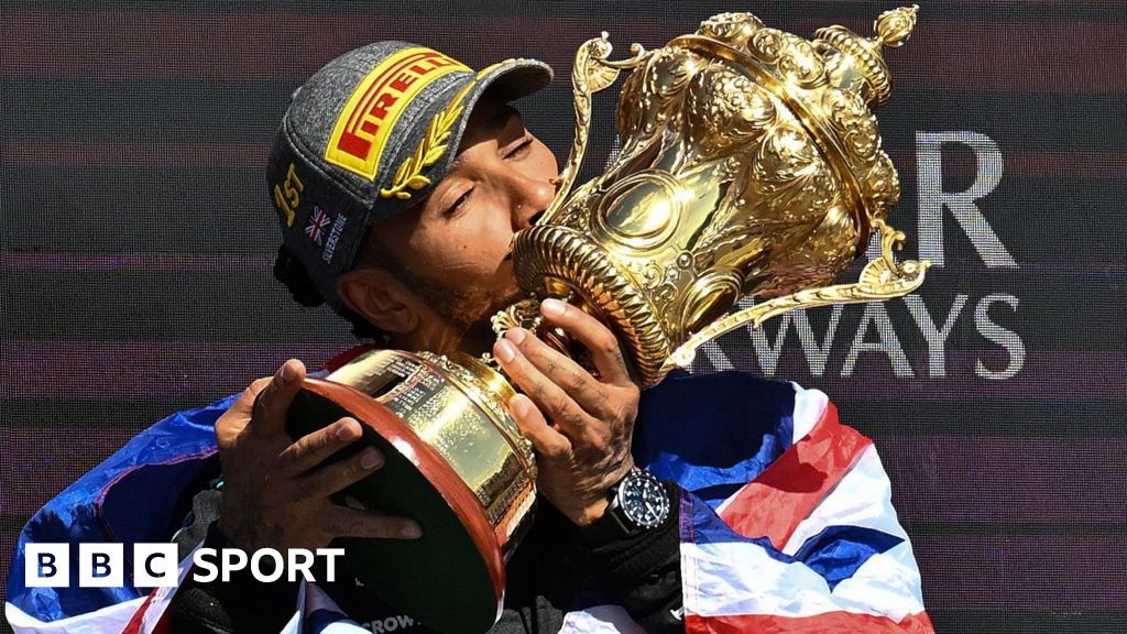 Lewis Hamilton kisses the trophy with a Union flag draped over his shoulders after winning the 2024 British Grand Prix