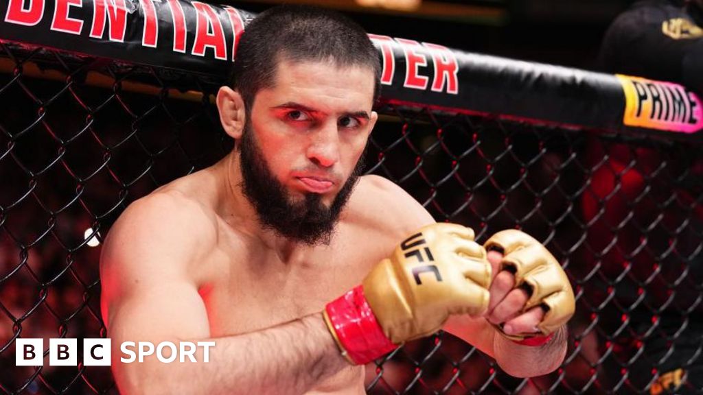 Islam Makhachev sticks out his tongue leaning against the UFC octagon as he prepares to fight