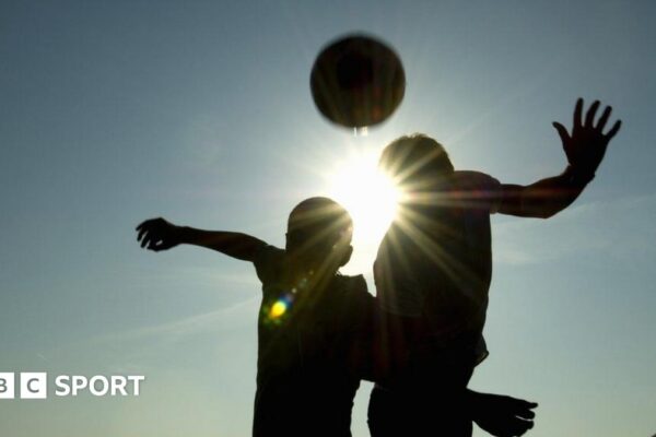 A silhouette of two players heading a football