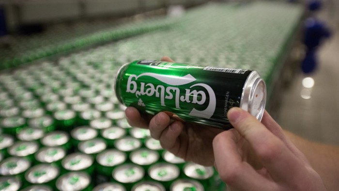 A worker checks cans of Carlsberg beer as they move along the production line at the OAO Baltika brewery, operated by Carlsberg A/S, in Saint Petersburg, Russia