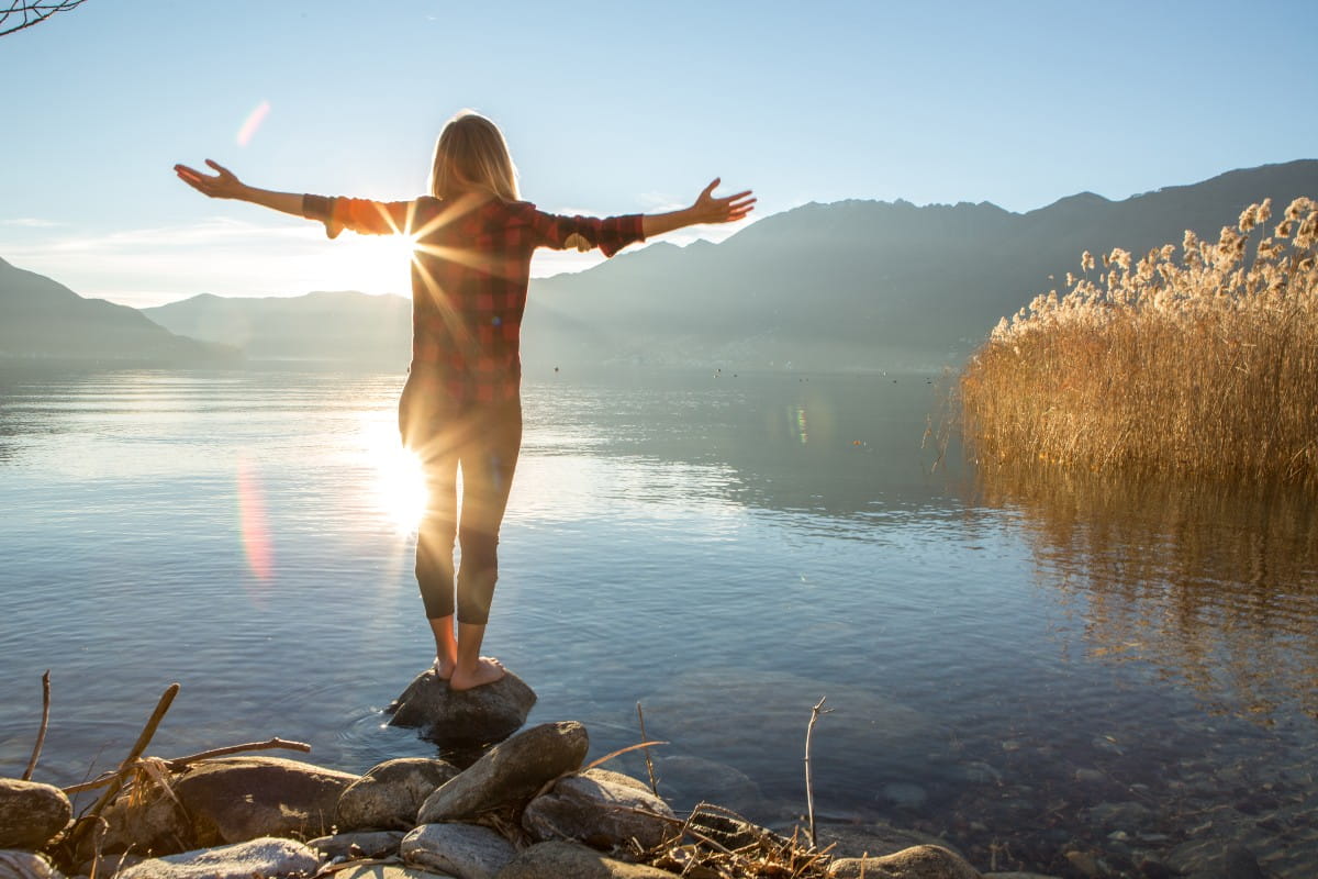 Young cheerful woman by the lake enjoying nature