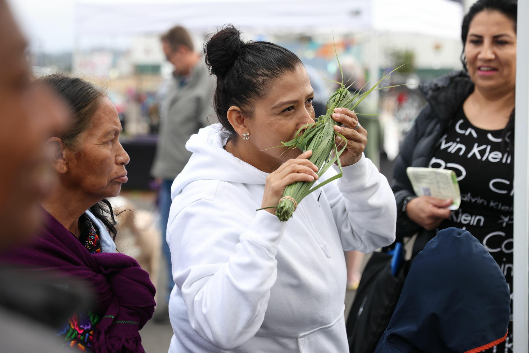 A Latina smells a lemon tea bunch at the Newport Farmers Market.