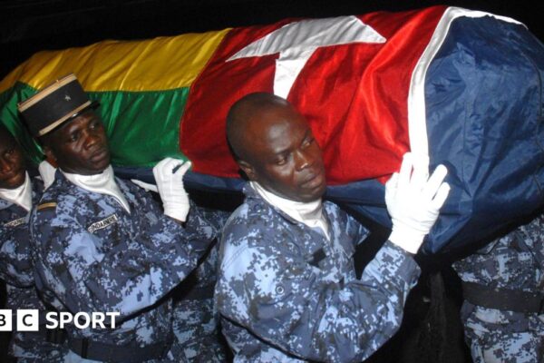 Togo bus attack 2010: Emmanuel Adebayor recalls ambush in Angola Four gendarmes, wearing blue digital camouflage fatigues and white gloves, carry a coffin bearing the Togolese flag on their shoulders