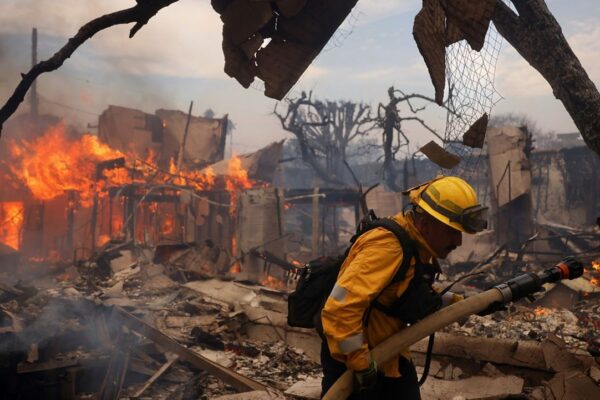 A firefighter battles the Palisades Fire around a burned structure in the Pacific Palisades neighborhood of Los Angeles, Jan. 8, 2025. (AP Photo/Etienne Laurent)