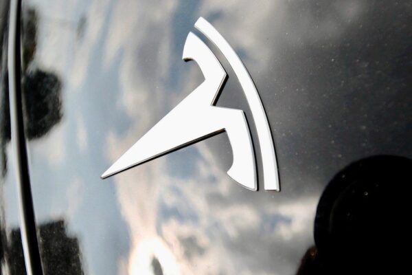 Clouds are reflected above the company logo on the hood of a Tesla vehicle outside a showroom in Littleton, Colo. (AP Photo/David Zalubowski, File)