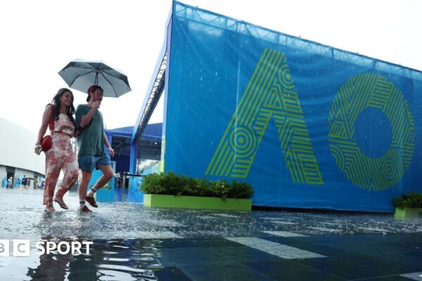Fans arrive at Melbourne Park under an umbrella