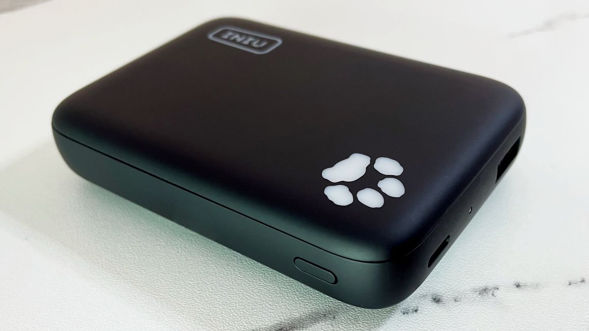 An iPhone is charging on the INIU B43 power bank which sits on a marble-effect surface.