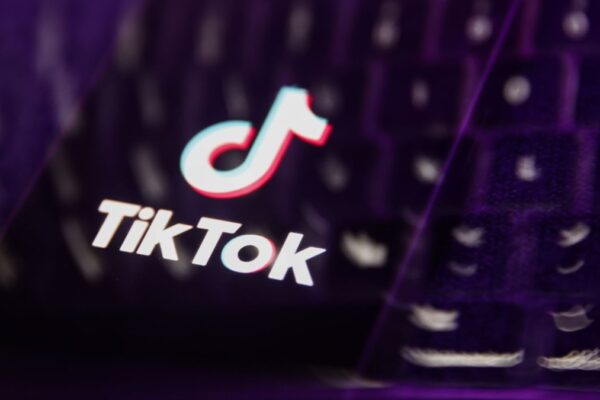 A laptop keyboard and TikTok logo displayed on a phone screen are seen in this multiple exposure illustration.