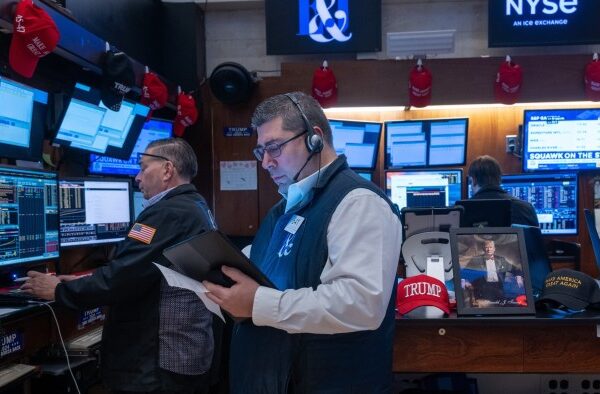 Traders work on the New York Stock Exchange next to a Donald Trump picture