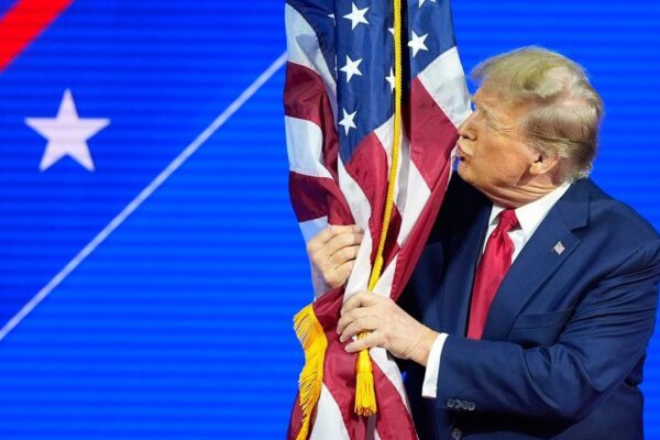 File photo of then presidential candidate Donald Trump hugs and kisses the American flag as he speaks at CPAC on Feb. 24, 2024. (AP Photo/Alex Brandon)