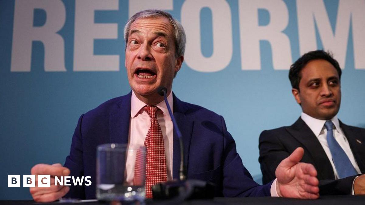 Nigel Farage in a blue suit and red tie makes a point at a Reform UK press conference. Reform UK chairman Zia Yusuf in a dark suit and blue tie sits next to him, looking to the right