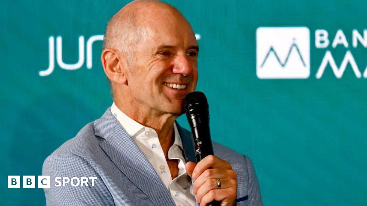 Adrian Newey speaking into a microphone at an Aston Martin news conference