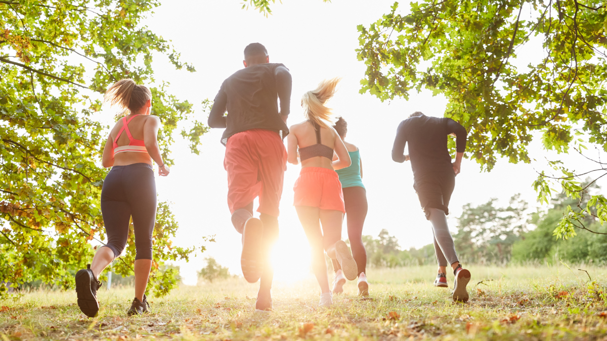 people running away on a nature trail with the sun setting ahead of them