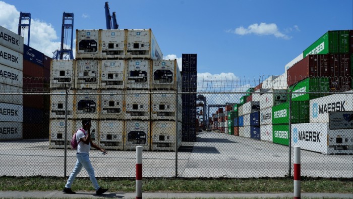A man walks past a chain-link fence topped with barbed wire near the entrance of Balboa Port in Panama City