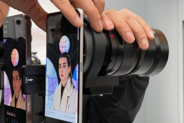 A man mounting a large zoom lens onto a phone