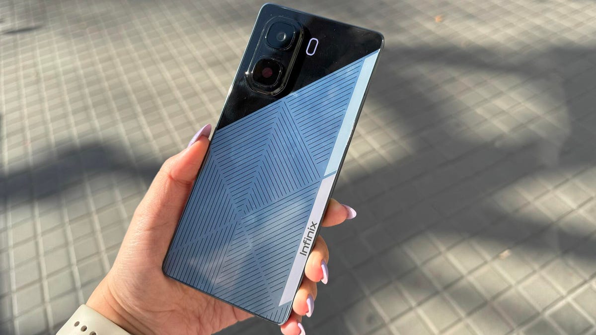 A hand holding a phone with a shiny gray-and-patterned back cover.