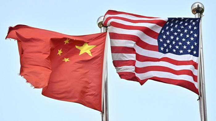 Chinese and US flags waving side by side against a clear sky