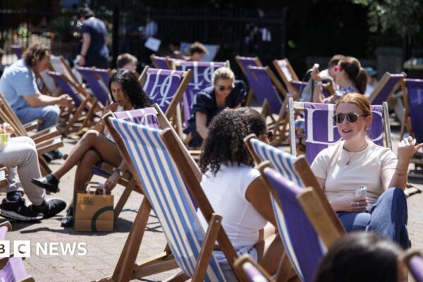 People sit on deckchairs during sunshine in London