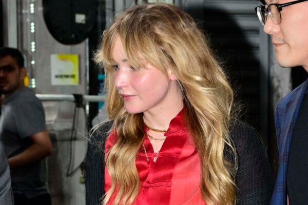 Jennifer Lawrence wears a black lace skirt with a red silk shirt and flat pumps