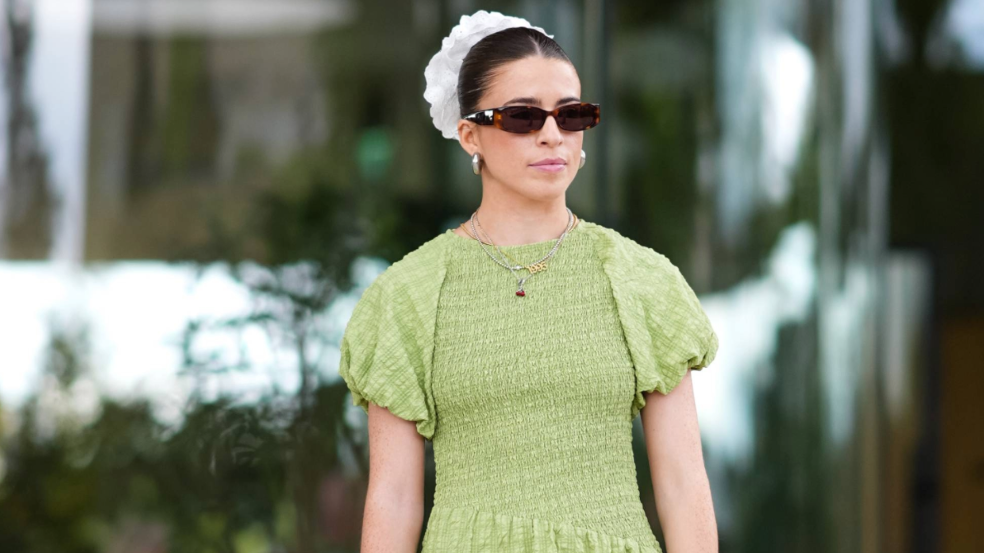 COPENHAGEN, DENMARK - AUGUST 08: A guest wears black sunglasses, silver earrings, white scrunchie, light green puffy sleeve midi dress, silver metallic bag, white socks, silver sneaker shoes, outside Marimekko, during the Copenhagen Fashion Week Spring/Summer 2024-2025 on August 8, 2024 in Copenhagen, Denmark. (Photo by Edward Berthelot/Getty Images)