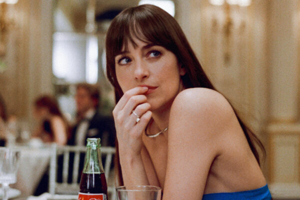 Dakota Johnson sits at a table with a look of mild upset in Materialists.