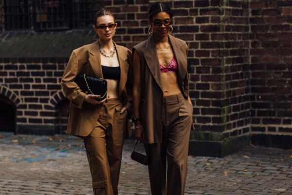 two attendees at Copenhagen spring 2023 fashion week wearing sunglasses, crop tops, and brown suits