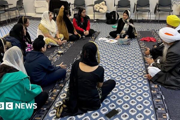 A group of people sit in a circle at a gurdwara