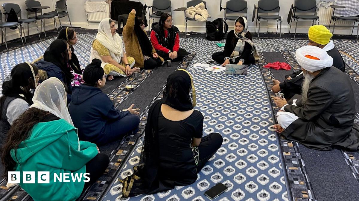 A group of people sit in a circle at a gurdwara