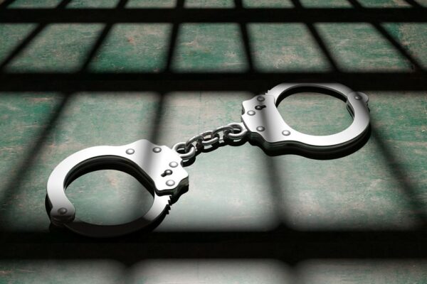 Prison concept. Jail bars and metal handcuffs on the floor, dark background