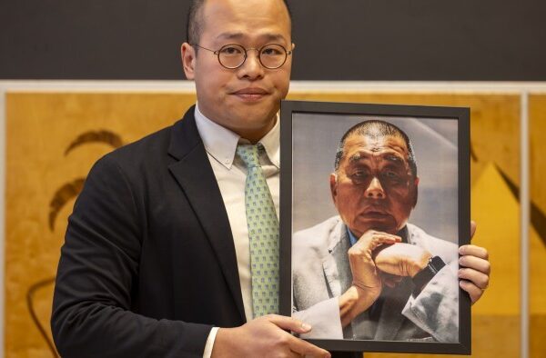 Sebastien Lai holds a framed photograph of his father