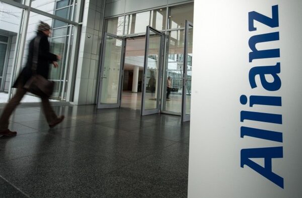 A man walks past the logo of Allianz at the entrance to an office building