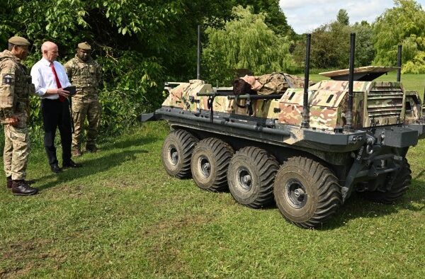 Defence secretary John Healey is flanked by two military personal as he operates an unmanned ground vehicle
