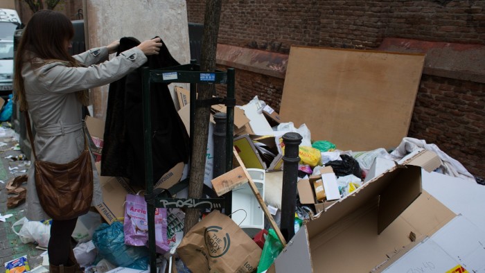 A girl looks at a piece of clothing dumped on a pile of rubbish which blocks a sidewalk during the fourth day of a garbage collectors strike, in Madrid, Spain