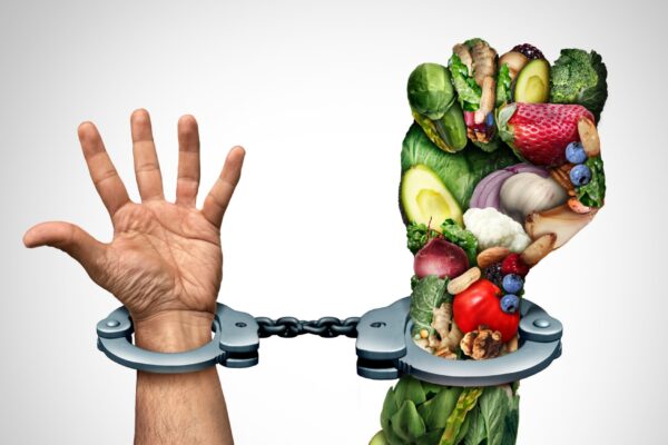 Human hands shackled in cuffs with fruits and vegetables