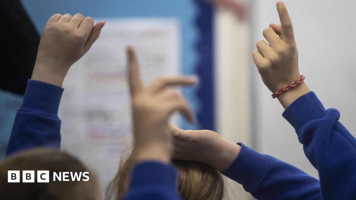 Schoolchildren raising their hands in a classroom
