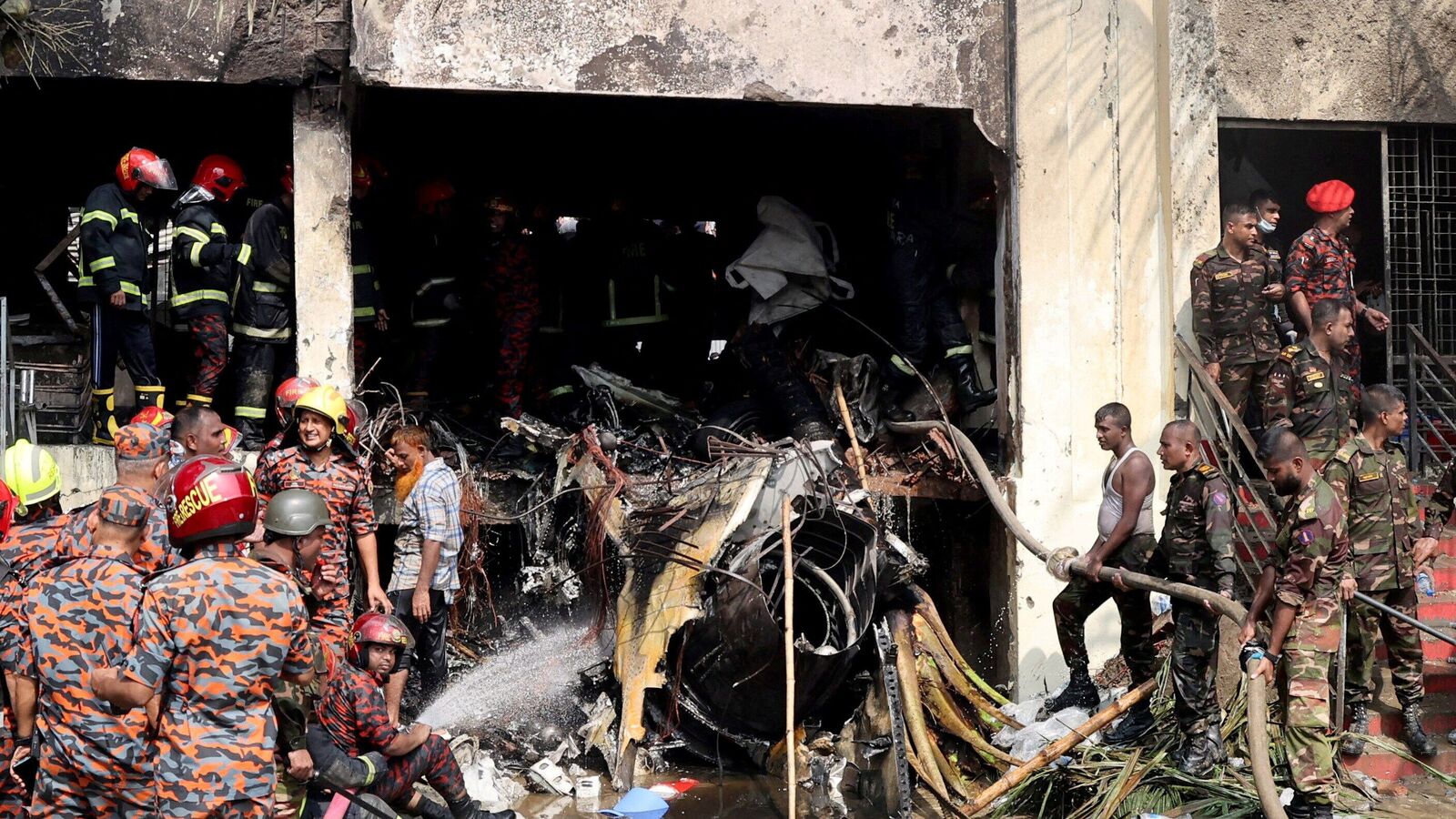 Firefighters and army members work next to the wreckage of an air force training aircraft after it crashed into Milestone College campus, in Dhaka, Bangladesh, July 21, 2025. REUTERS/Stringer     TPX IMAGES OF THE DAY
