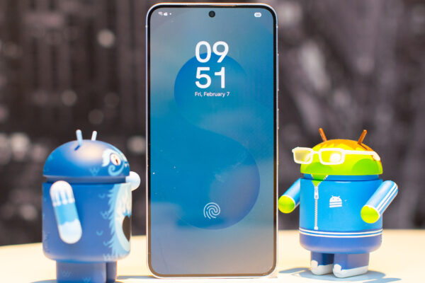 Samsung Galaxy S25 showing the lock screen with two adorable collectible Android figurines on each side looking interested