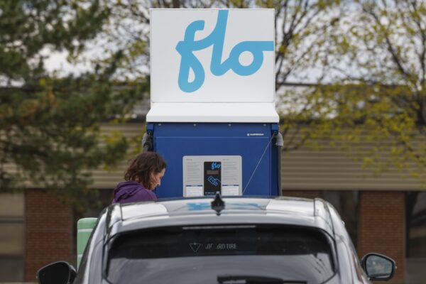A Flo EV recharge station with a driver and a gray vehicle in the foreground