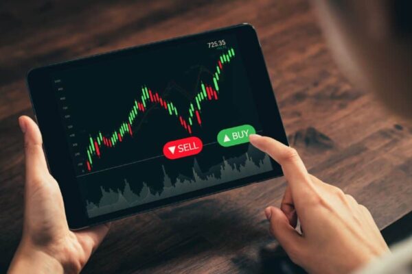 Could the stock market crash in the second half of 2025? Investor looking at stock graph on a tablet with their finger hovering over the Buy button